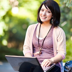 College student sitting on the ground with her computer in her lap