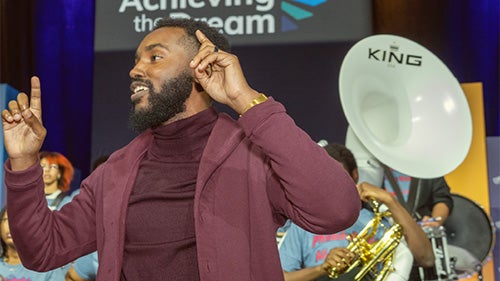 Achieving the Dream Network Connection newsletter cover featuring a speaker performing on stage at an Achieving the Dream event.