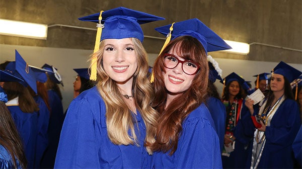 Two graduates smiling together after ceremony
