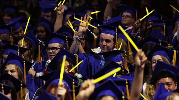 Graduates celebrating and waving glow sticks during ceremony