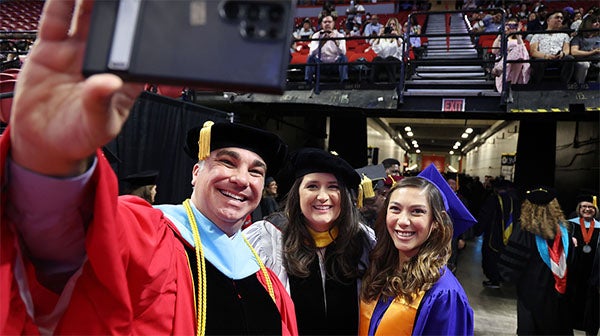 Faculty taking a selfie with graduates at commencement ceremony