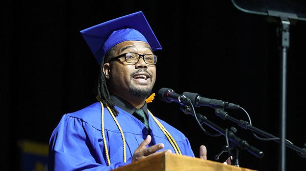 Graduate speaking at a podium during commencement ceremony.