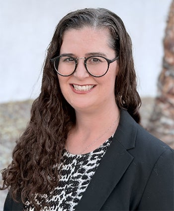 Portrait of Dr. Rachel Yoho smiling and wearing glasses and a black blazer.