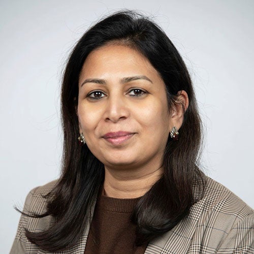 Professional headshot of a Jyoti Senthil wearing a plaid blazer.