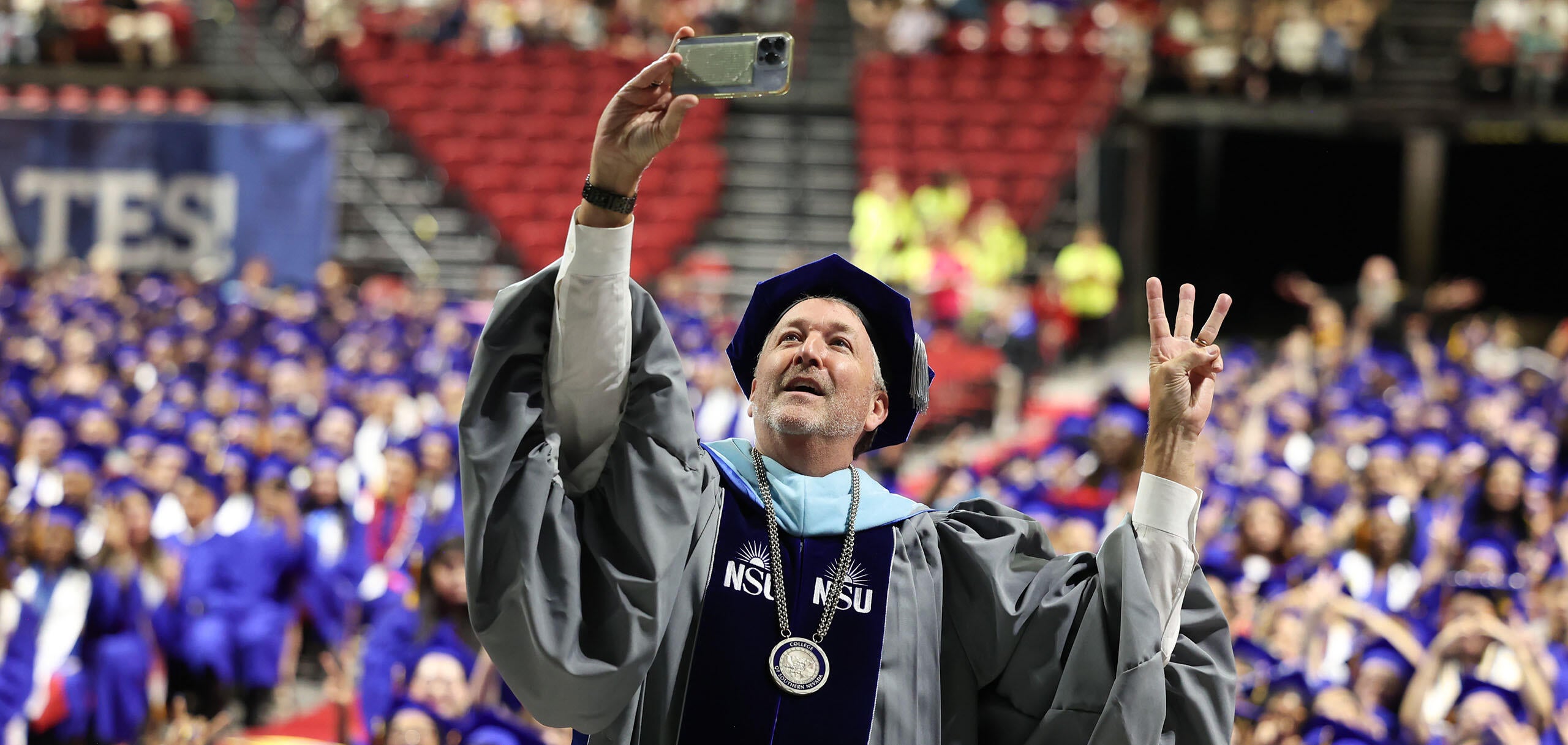 CSN President Dr. Stacy Klippenstein takes a selfie and flashes a hand sign while standing among graduates during a commencement ceremony at the Thomas & Mack Center.
