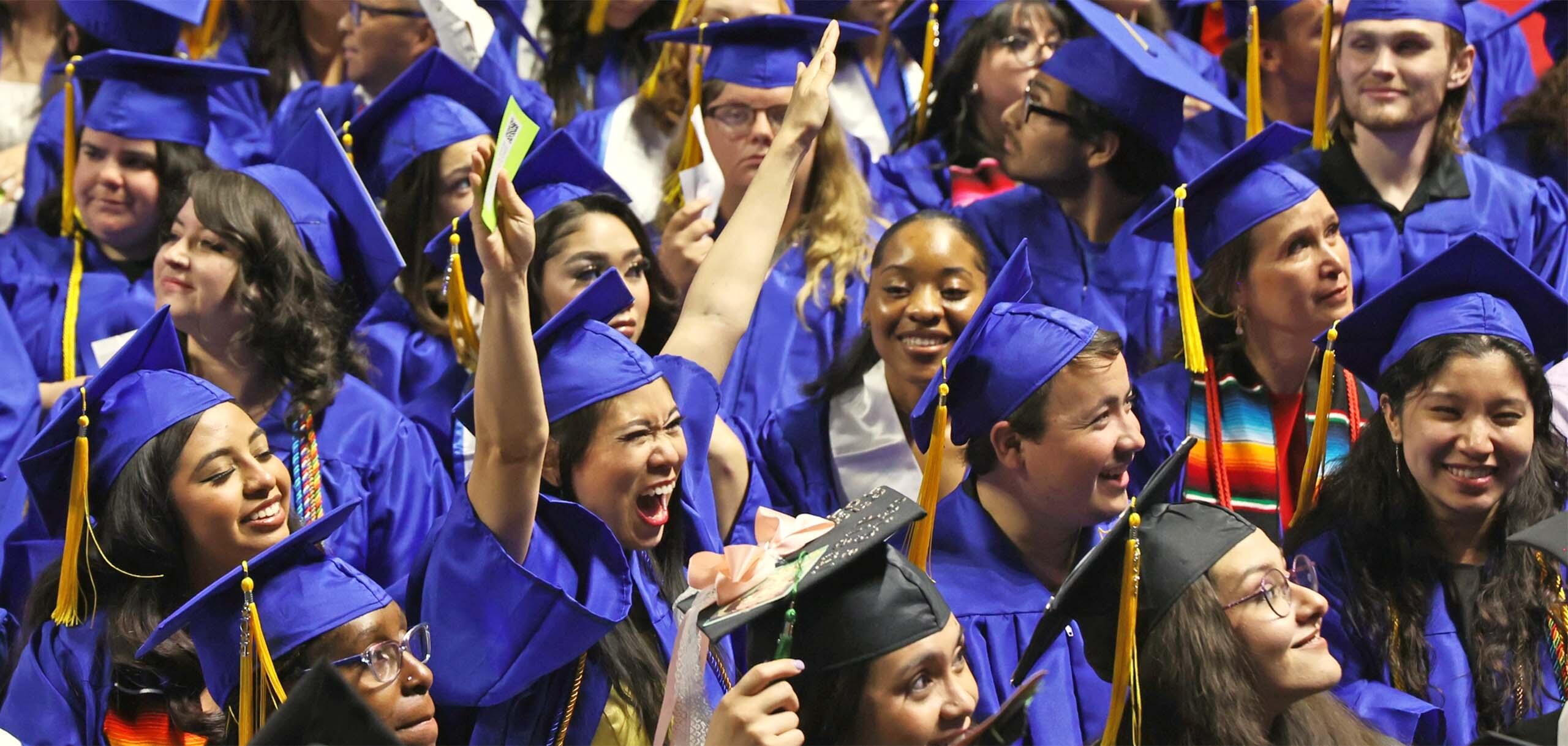 CSN graduates in caps and gowns celebrate enthusiastically among a crowd during commencement.