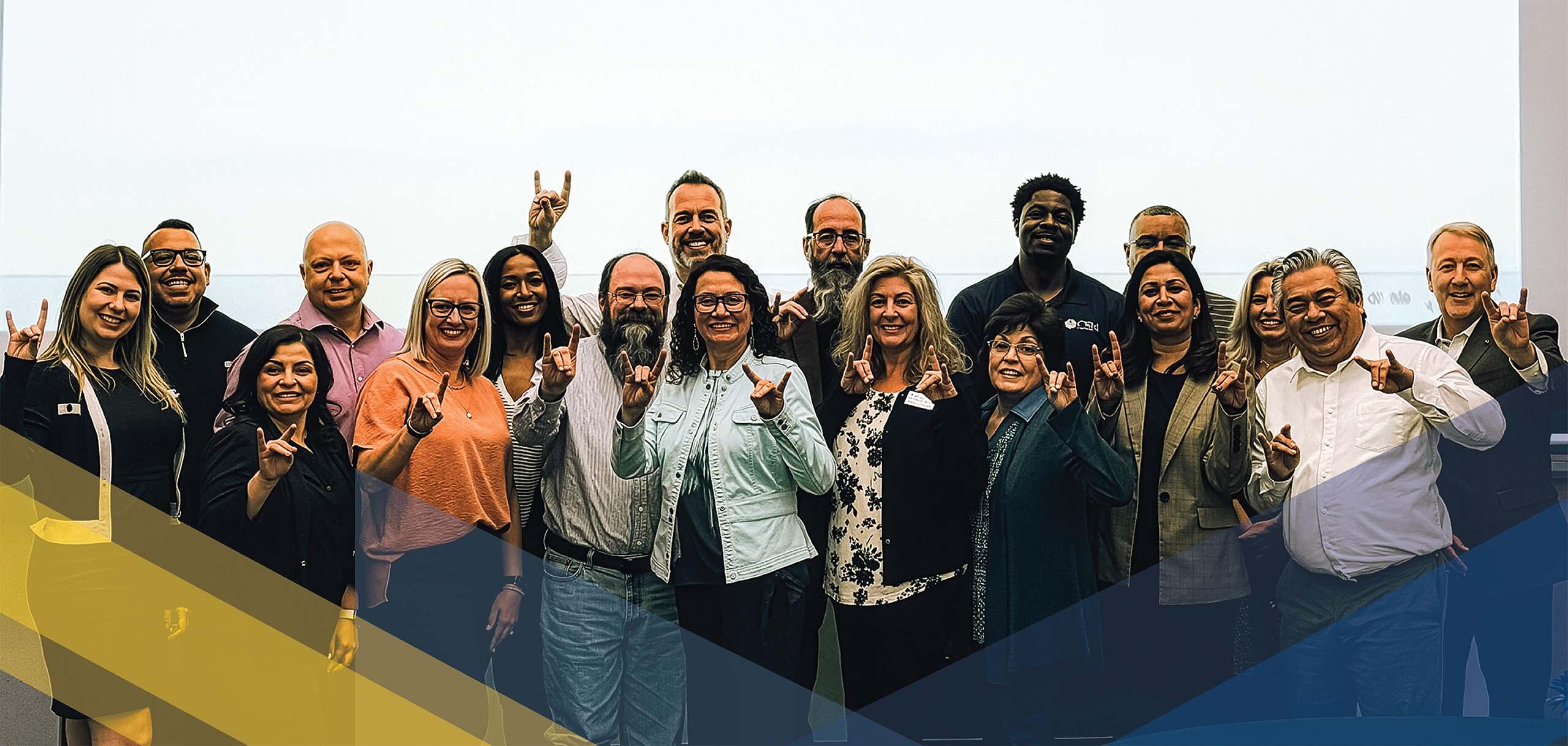 Members of CSN’s Strategic Taskforce pose together and make the Coyote hand sign during a group meeting.